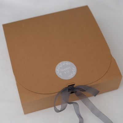 Caixa de cartão castanho com fita cinzenta e selo Napkin & CO