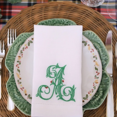 Conjunto de pratos decorativos com guardanapo branco bordado e talheres sobre mesa xadrez