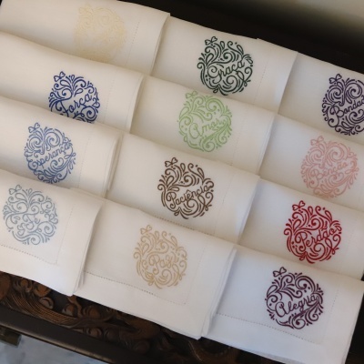 Guardanapos brancos bordados com palavras coloridas espalhados sobre madeira entalhada