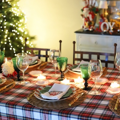 Mesa de jantar decorada para Natal com toalha xadrez e velas acesas