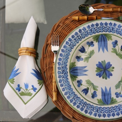 Conjunto de prato de cerâmica azul e verde e guardanapo com padrão floral com talheres e suporte de palha