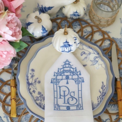 Louça azul e branca com padrão, guardanapo com letras DPS, abóboras decorativas e flores cor-de-rosa