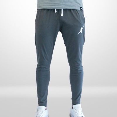 Calças desportivas cinza com cordão branco e logo branco, usadas com t-shirt cinza e sapatilhas brancas