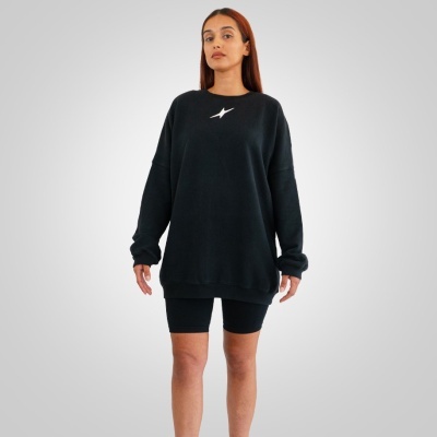 Mulher com sweat preto e calções justos pretos em fundo neutro