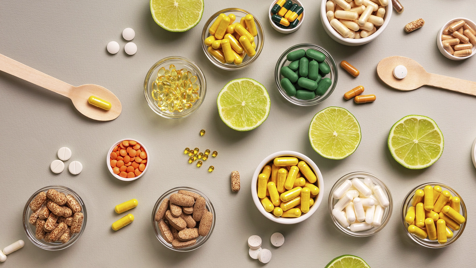 Cápsulas e comprimidos coloridos com fatias de lima verde sobre superfície clara