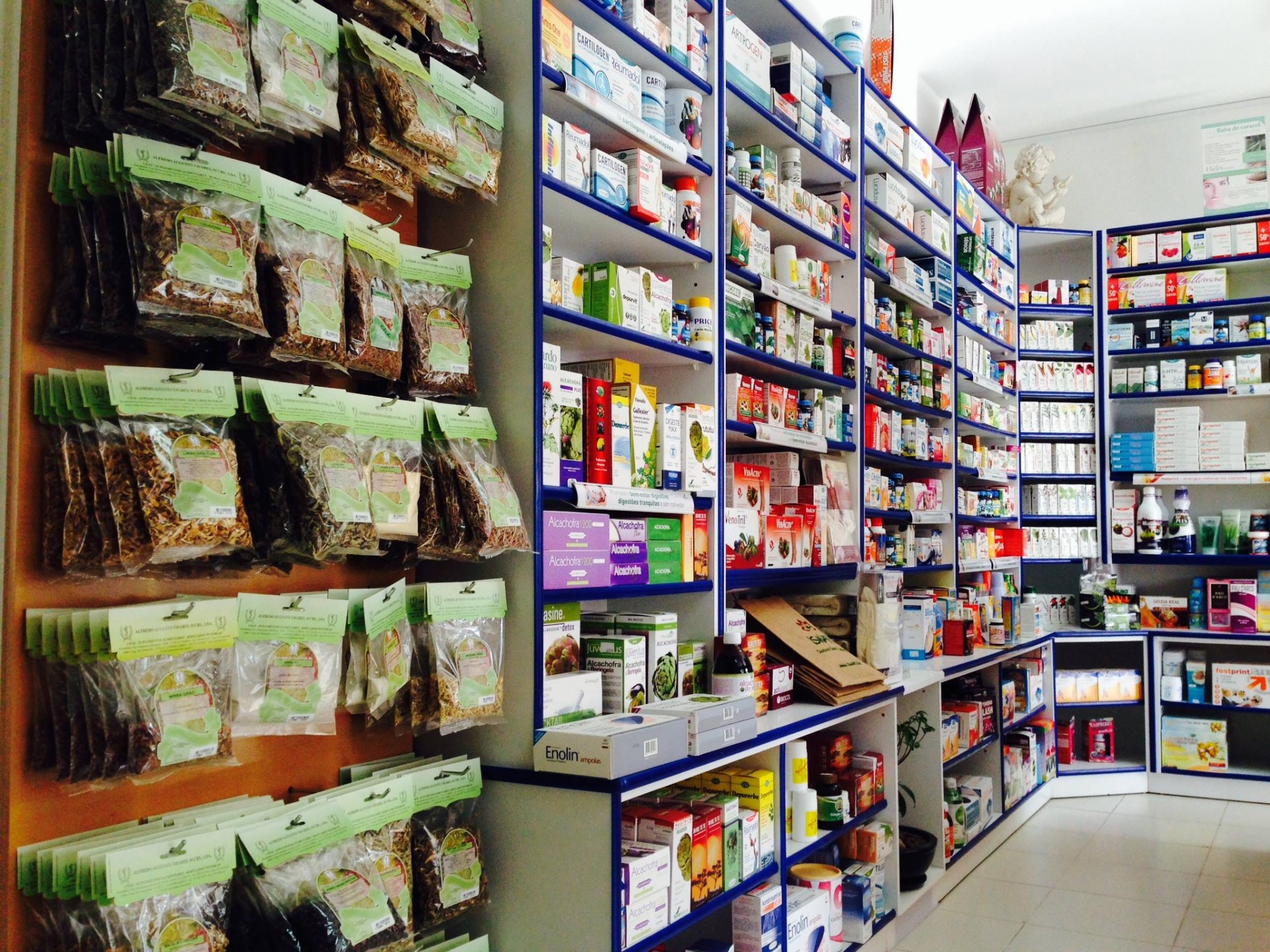 Prateleiras com produtos de saúde, frascos e pacotes de ervas secas numa loja bem iluminada