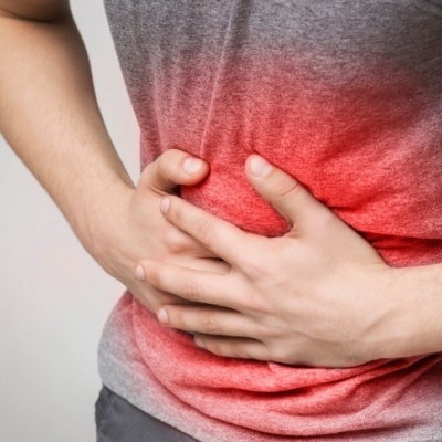 Pessoa com t-shirt cinza a segurar a barriga com efeito vermelho indicando dor