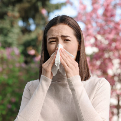 Mulher a assoar o nariz com lenço de papel branco ao ar livre