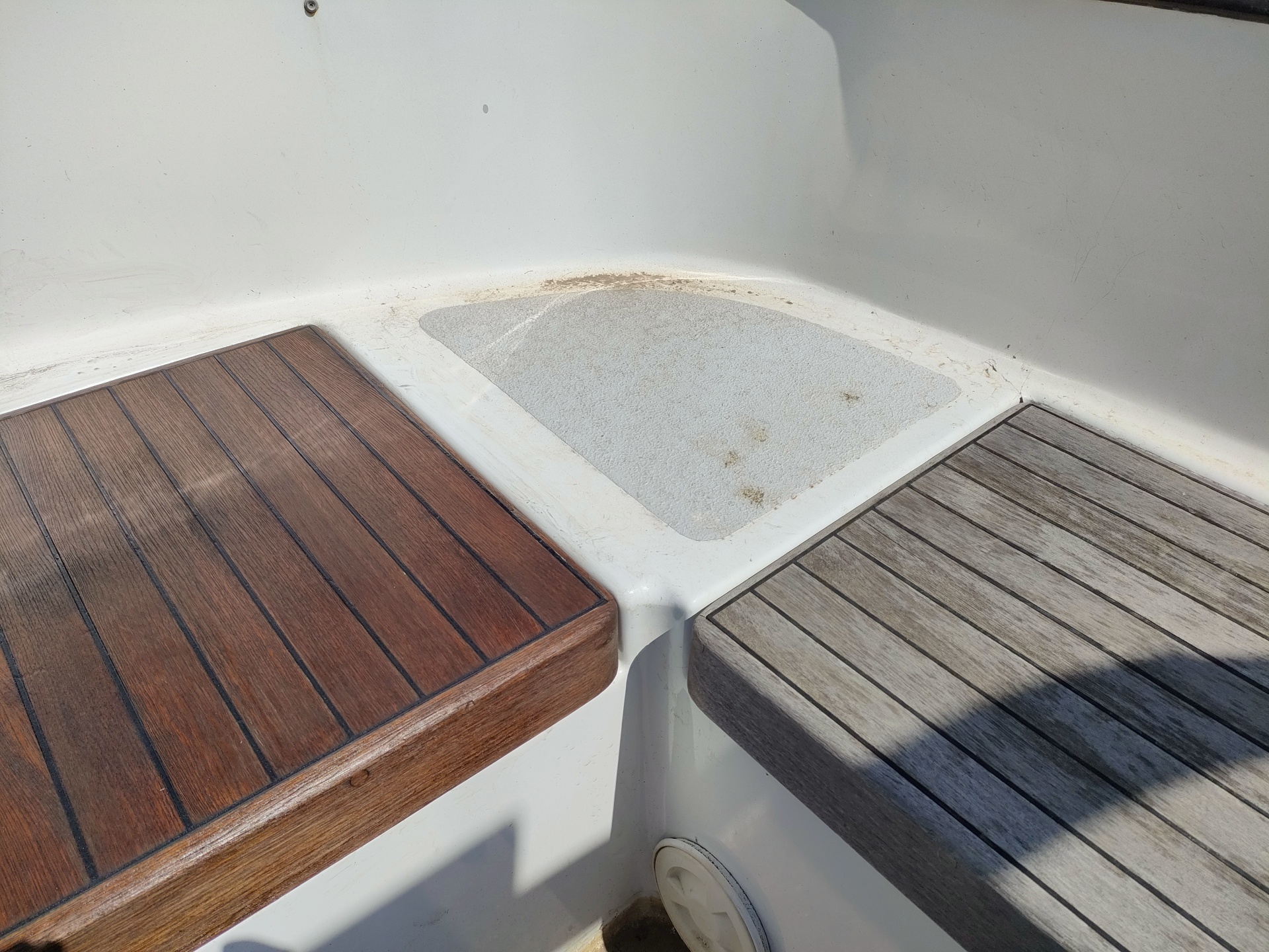 Superfícies de assento em madeira escura e clara com área central em plástico branco texturizado.