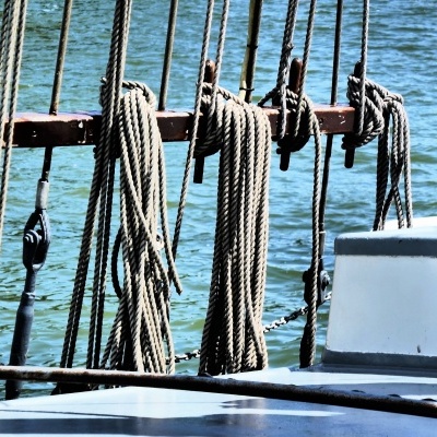 Corda grossa pendurada em suporte de madeira num barco com água ao fundo