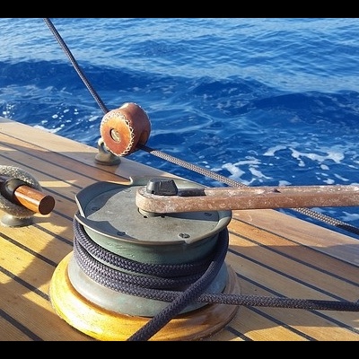 Guinchos com cordas em convés de madeira de barco no mar azul