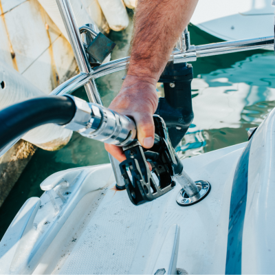 Bomba de combustível preta e prateada a abastecer um barco branco perto de um cais