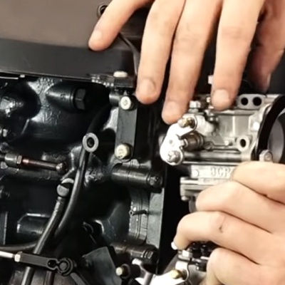 Motor preto de máquina com peças metálicas e mãos humanas manipulando uma peça prateada