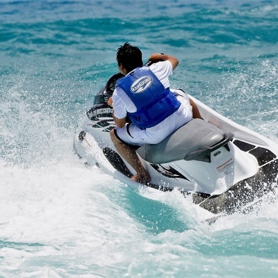 Pessoa de colete azul em jet ski branco no mar com ondas
