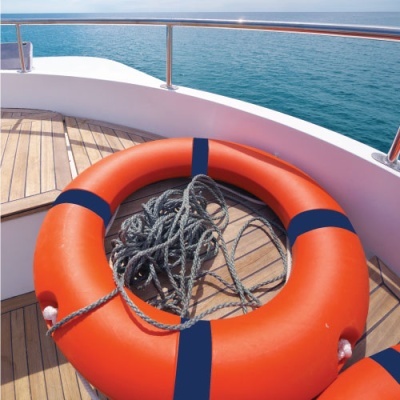 Boia salva-vidas laranja com faixas azuis e corda em convés de barco com vista para o mar