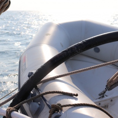 Bote insuflável cinzento claro com estruturas e cordas a bordo de um barco no mar