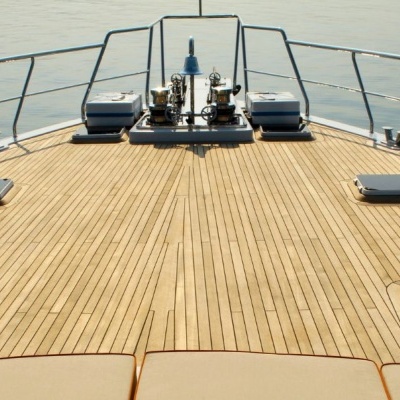 Convés de iate em madeira clara com guarda-corpos cromados sobre água