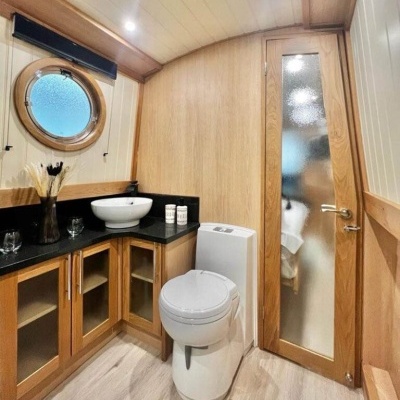 Casa de banho com lavatório, sanita, armários de madeira e janela circular