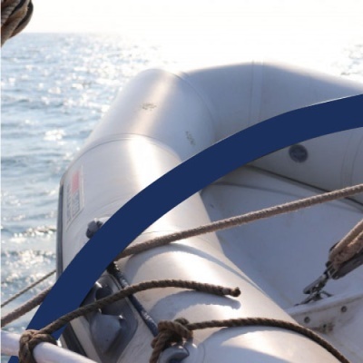 Barco insuflável cinza claro com cordas marrons e mar ao fundo