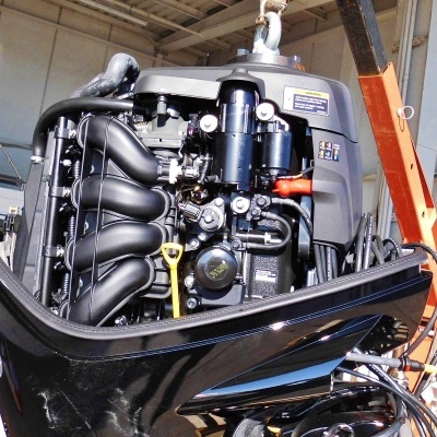 Motor de popa preto instalado em oficina com guindaste laranja