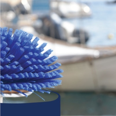 Escova azul com cerdas de plástico perto de água e barco