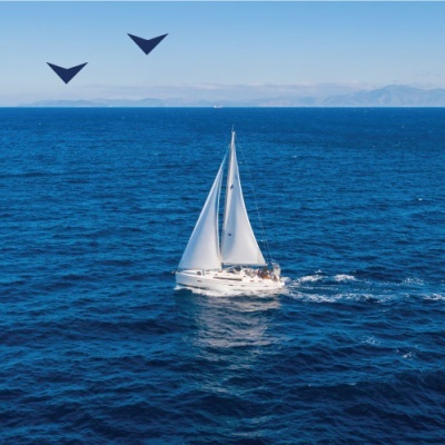 Veleiro branco com vela branca navegando em mar azul escuro