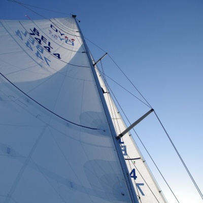 vela branca de veleiro com números azuis contra céu azul