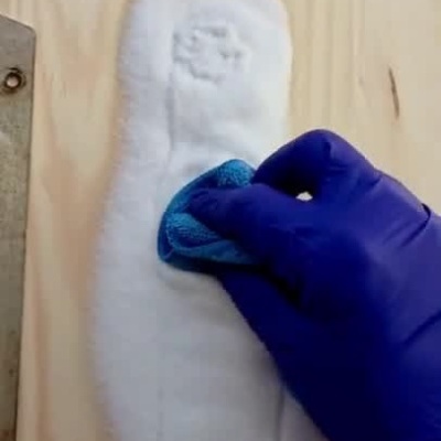 Duas ferragens metálicas sujas são limpas com espuma e pano azul, mostrando antes e depois.