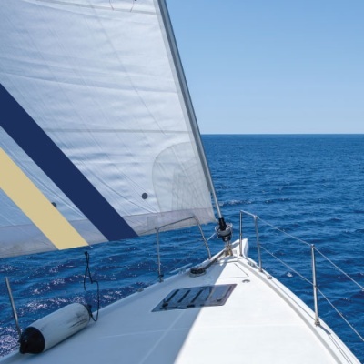 Proa de veleiro branco no mar com vela branca listrada