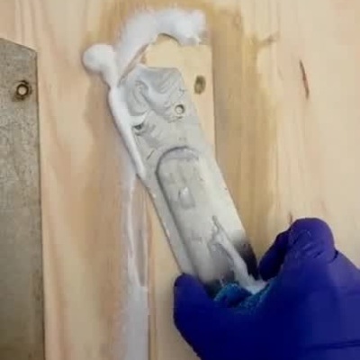Limpeza de peça metálica antiga em superfície de madeira com espuma e pano.