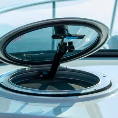 Janela de escotilha redonda de vidro e metal preta aberta num barco branco