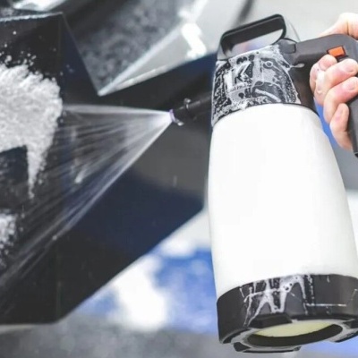 Pulverizador manual branco e preto a limpar carro preto com espuma