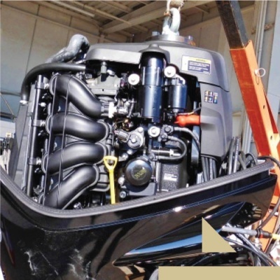 Motor de popa de barco preto e cinza com tubos e alavanca amarela em oficina