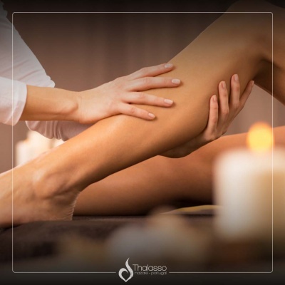 Pessoa a receber massagem na perna num ambiente relaxante com velas e luz quente