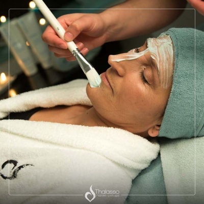 Mulher recebendo tratamento facial com creme e pincel em spa