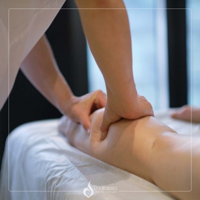 Massagem num braço com fundo de janela desenfocada e logo Thalasso.