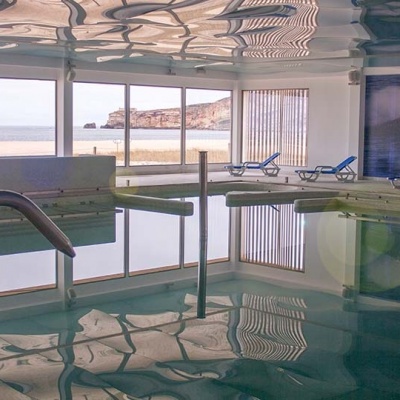 Piscina interior com janelas grandes e vista para o mar