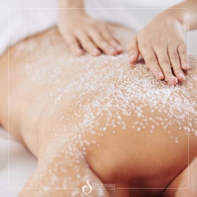 Pessoa a receber massagem com cristais granulados nas costas e mãos aplicando o produto