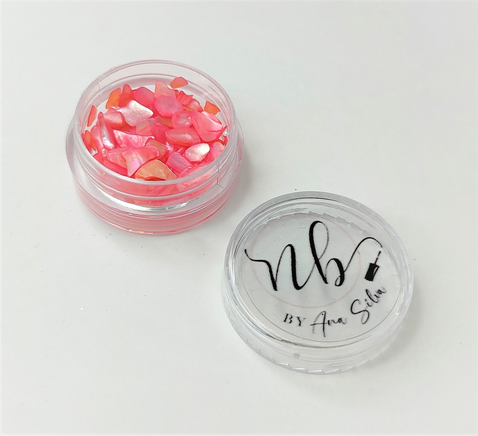 Frasco pequeno transparente com pedaços decorativos rosa e tampa com texto preto