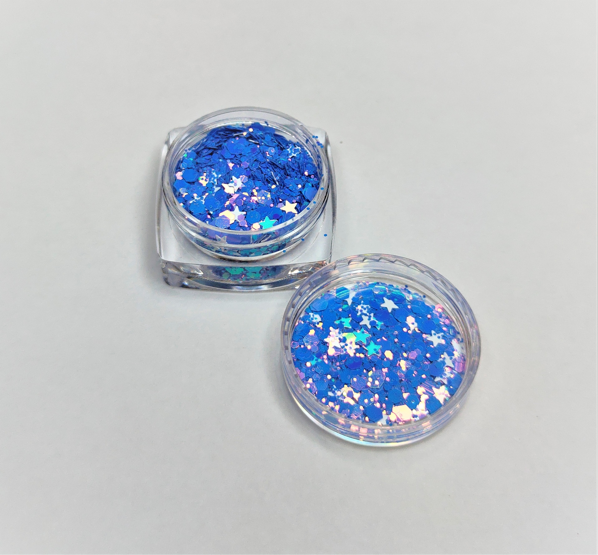 Dois recipientes transparentes com glitter azul em forma de estrelas