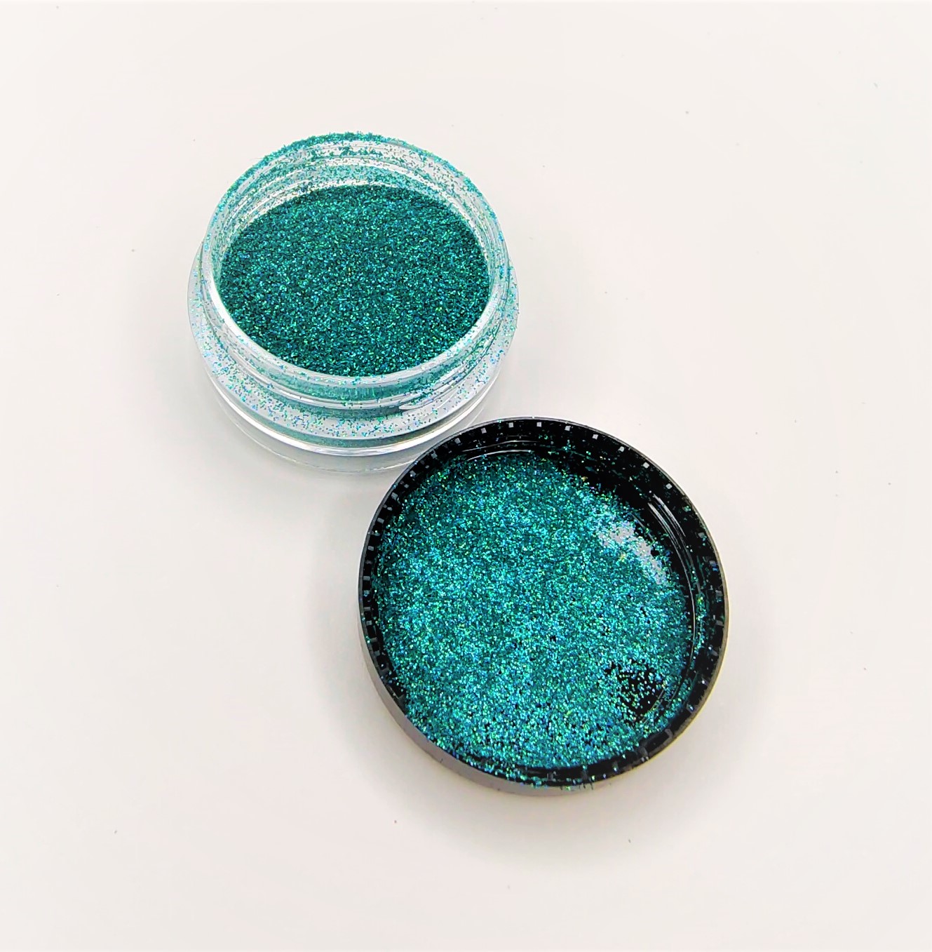Pote transparente com glitter azul esverdeado e tampa preta removida