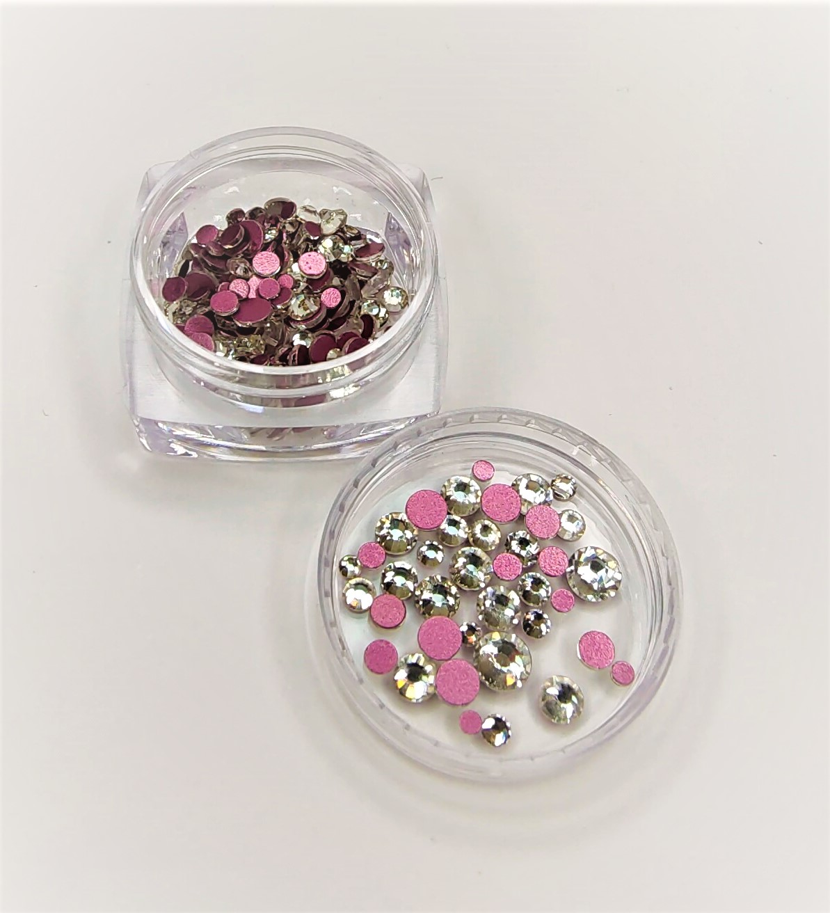 pedrinhas decorativas prateadas e cor de rosa em recipientes transparentes