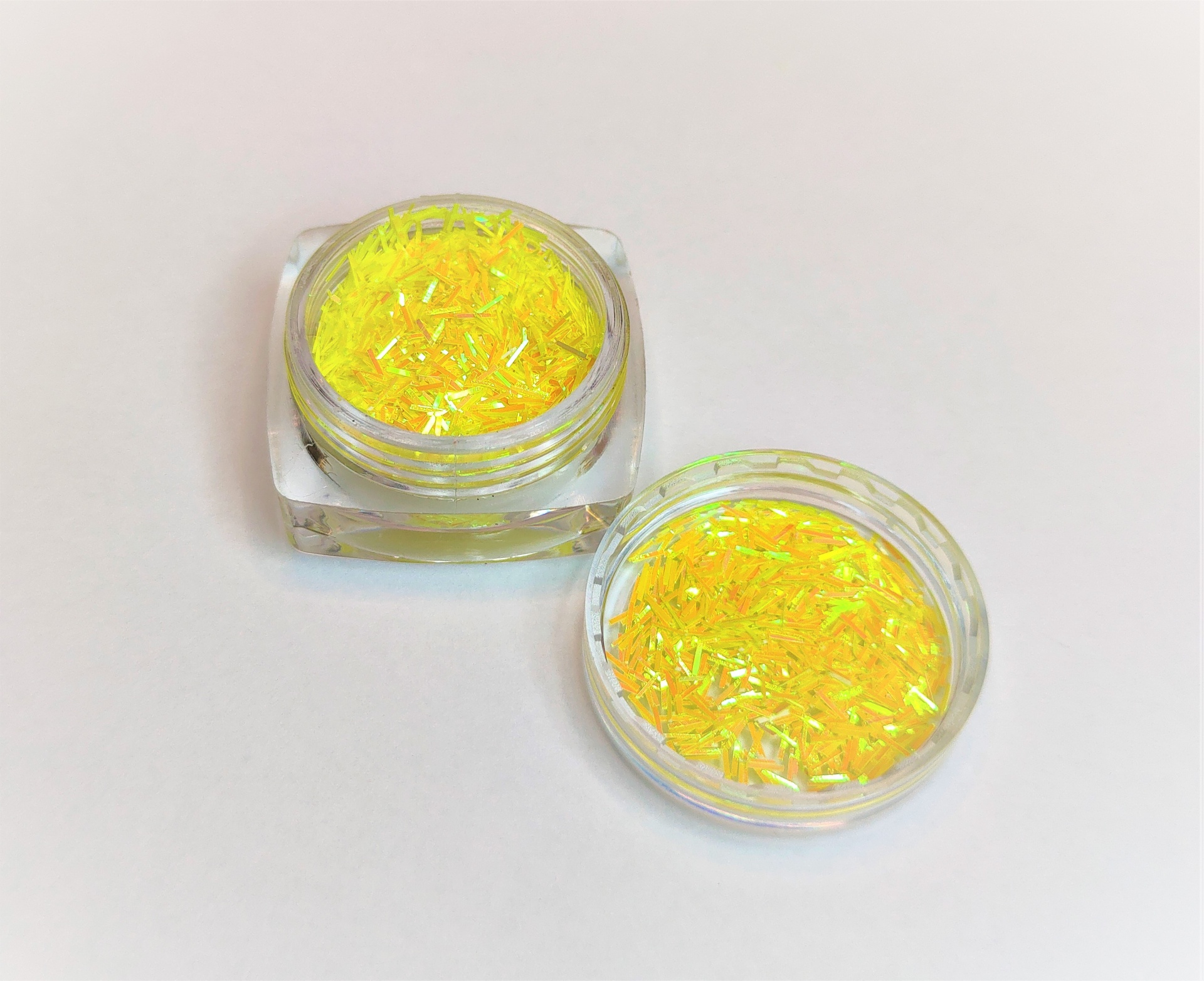 Recipientes com glitter amarelo iridescente em fundo branco