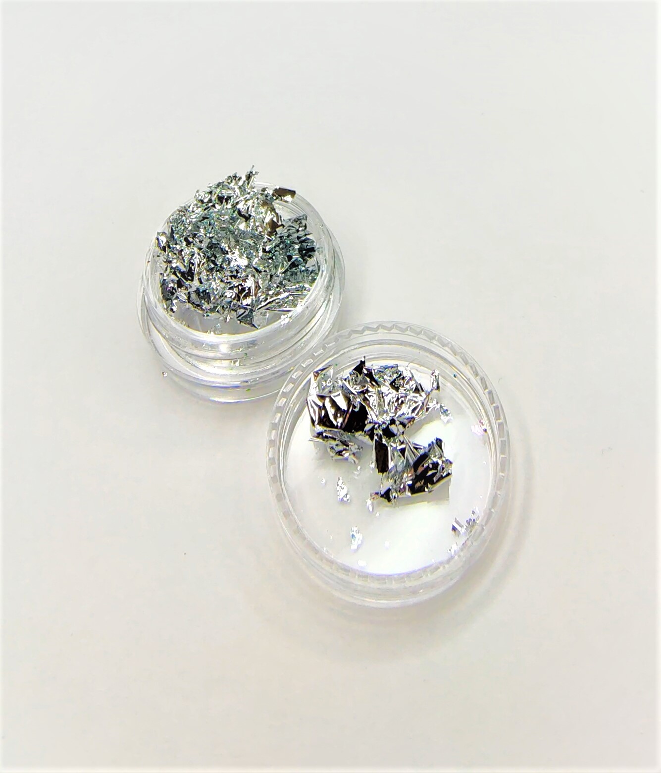 Folhas metálicas prateadas em recipientes transparentes