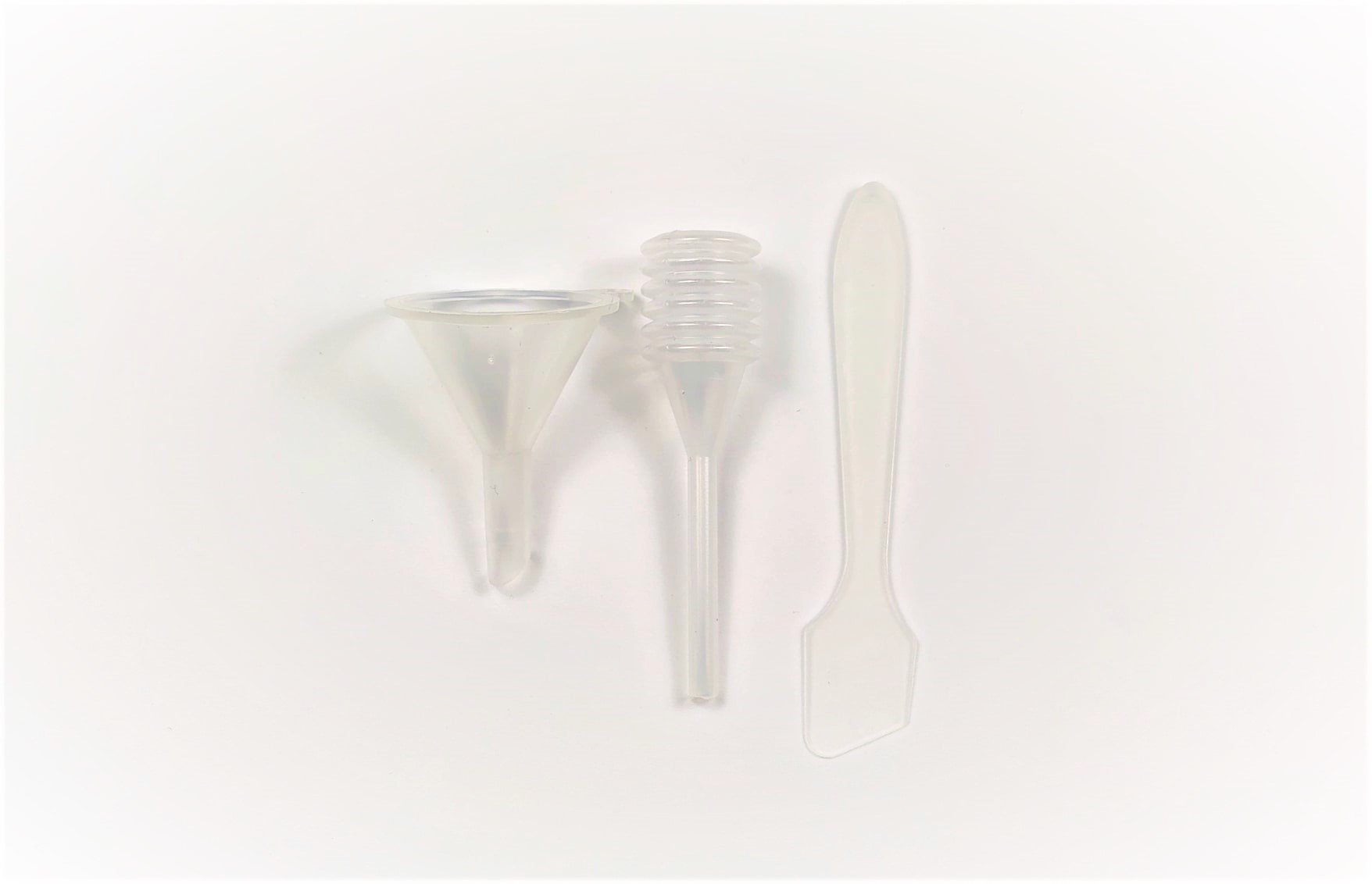 Três ferramentas de plástico transparente: dois funis e uma espátula, sobre fundo branco.