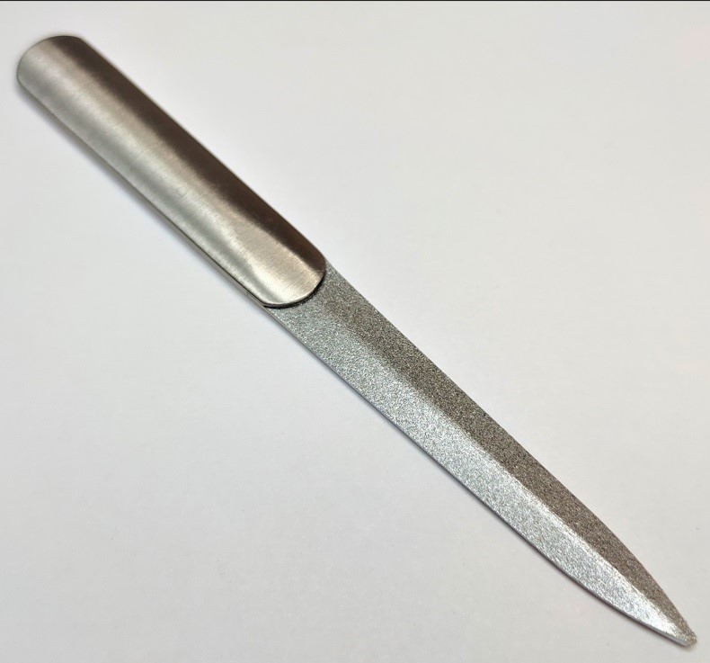 Lima para unhas em metal com superfície texturizada e fundo branco