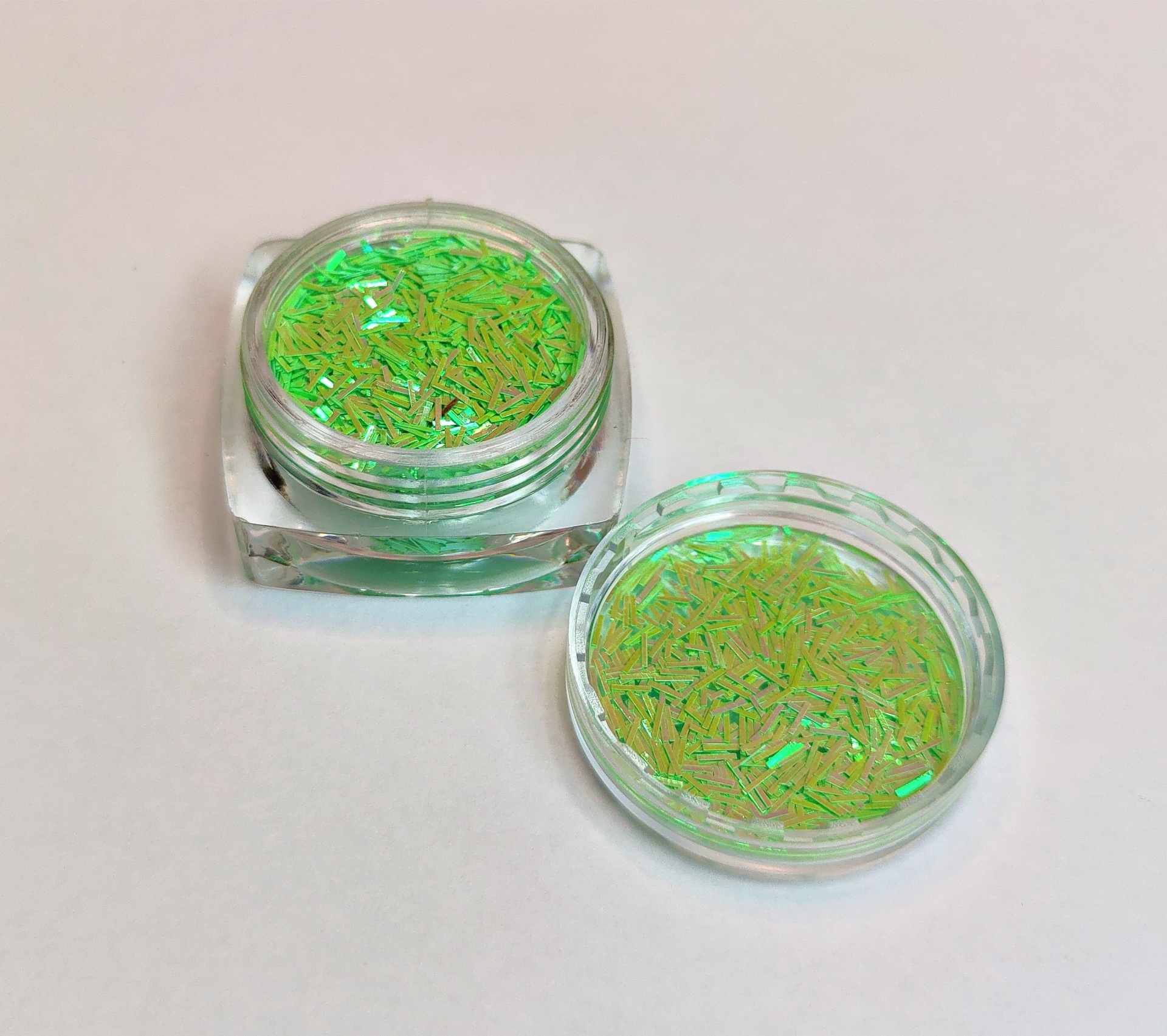 Dois pequenos frascos transparentes com glitter verde brilhante
