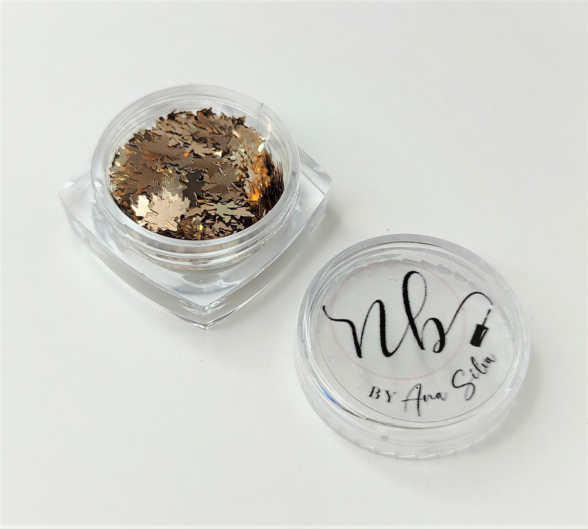 Pequeno frasco transparente com partículas douradas decorativas e tampa com texto preto