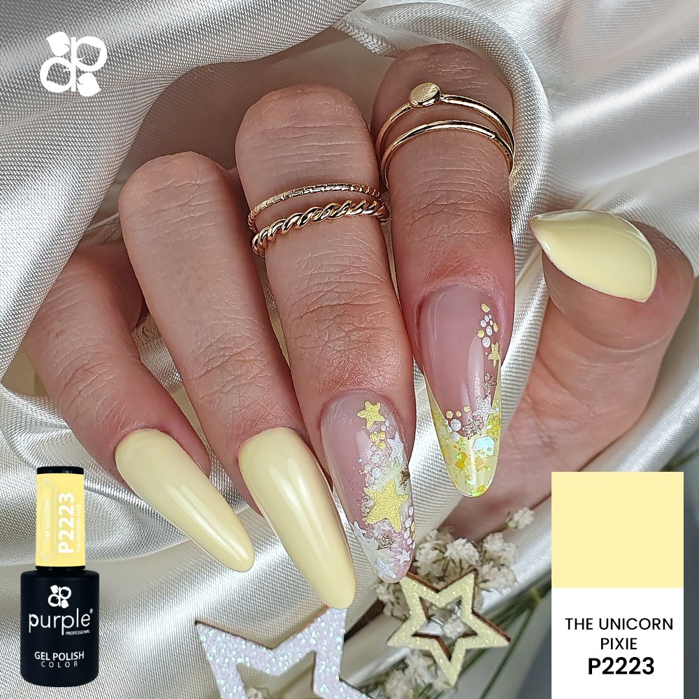 Mãos com unhas amarelas gel e decoração floral com anéis dourados e estrelas decorativas.