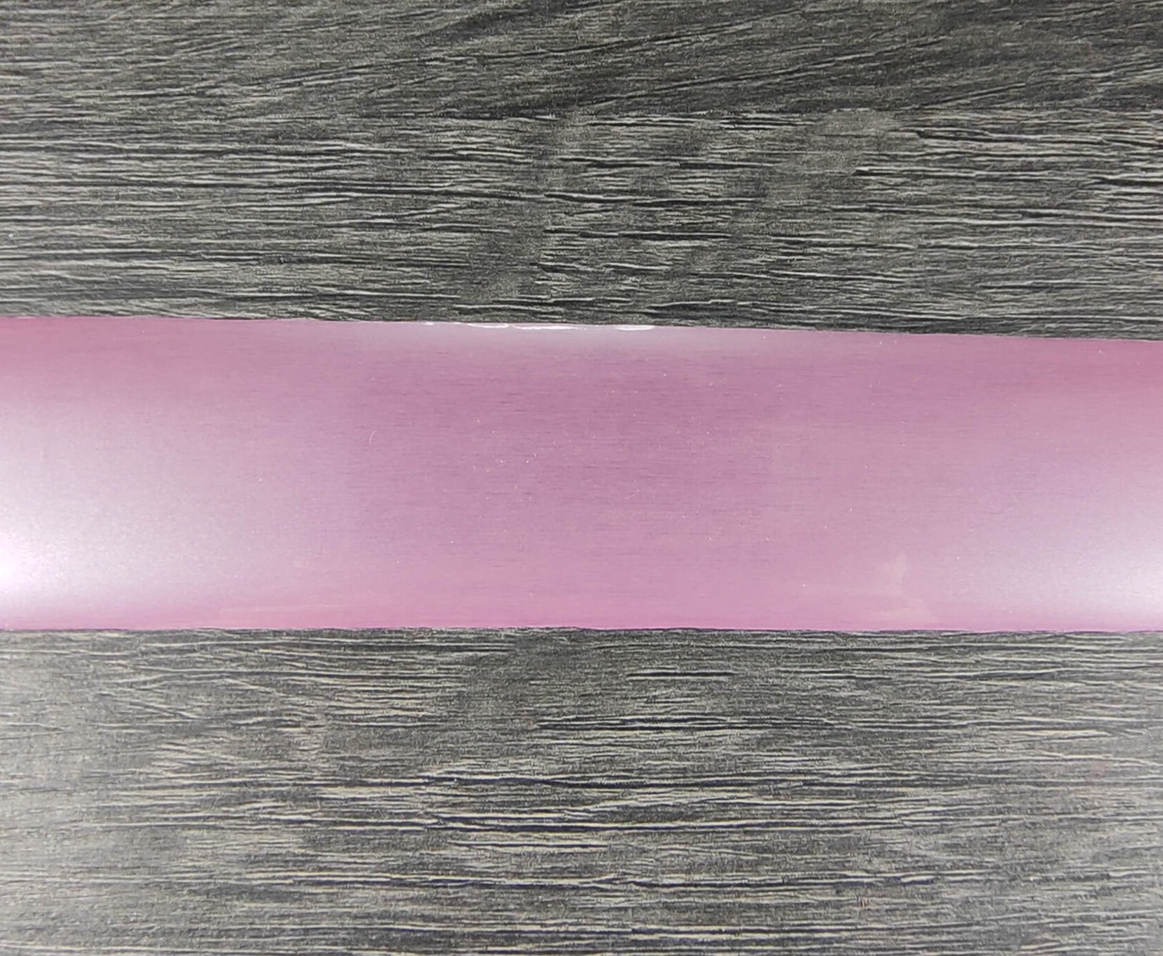 Faixa de tecido rosa claro sobre superfície de madeira escura